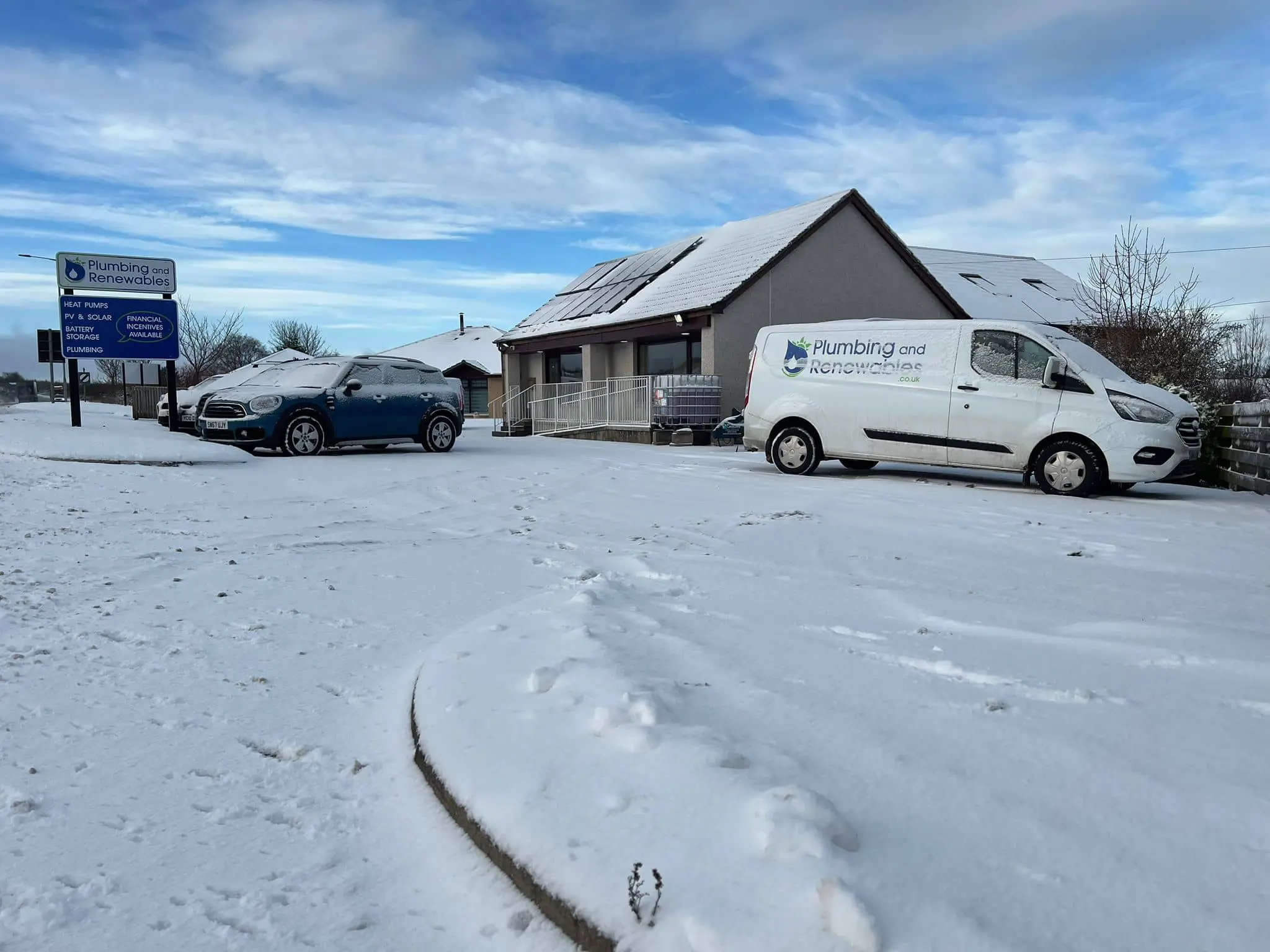 Snow-covered vehicles outside plumbing business